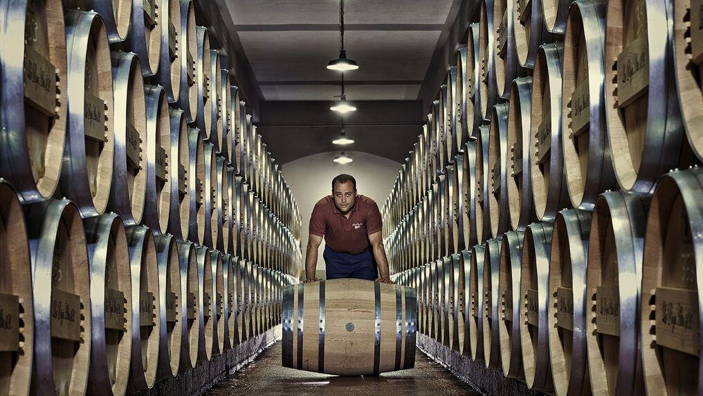 Ein Mitarbeiter von La Rioja Alta rollt ein Barrique-Fass durch den Gang im Fasskeller