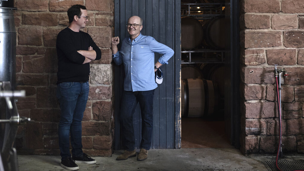 Paul Fürst und Sohn Sebastian stehen vor der halbgeöffneten Holz-Eingangstüre zum Fasskeller