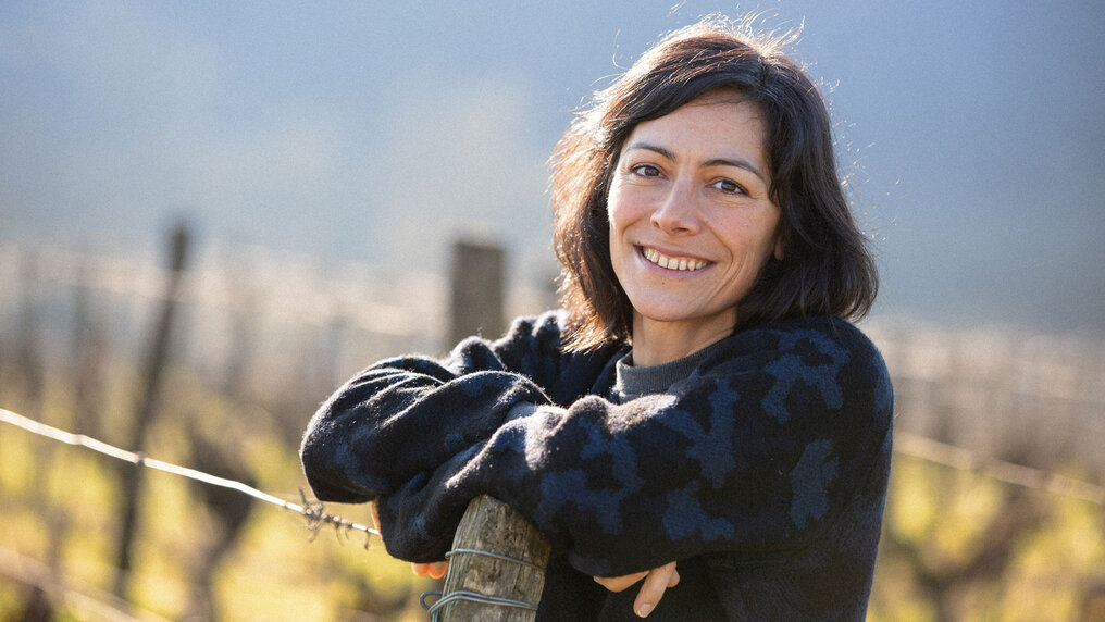 Emeline Calvez stützt sich auf einen Pfahl im Weinberg