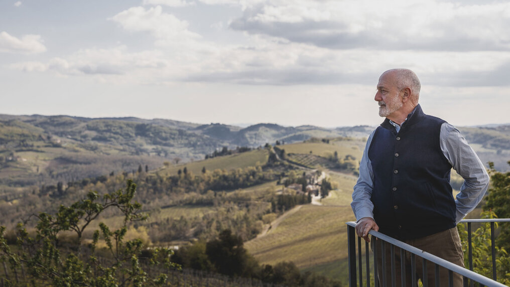 Alessandro Fonseca steht am Geländer der Weingutsterrasse und blickt in die Ferne. Hinter ihm erstreckt sich die idyllische Landschaft der Toskana.