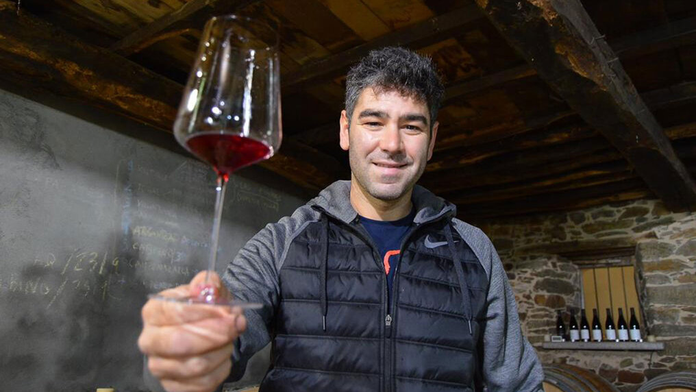 César Màrquez steht in seinem Weinkeller und hält ein Glas Rotwein in die Kamera