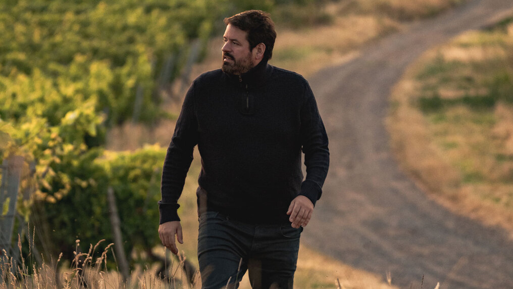 Markus Schneider walking along his vineyard, gazing into the distance
