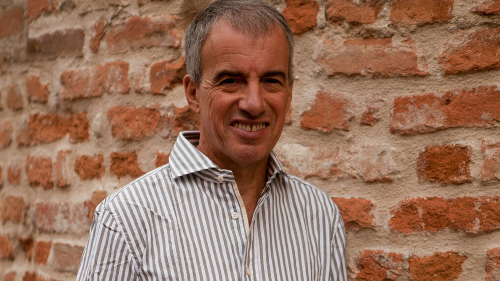 Portrait of Aldo Vacca in front of a brick wall.