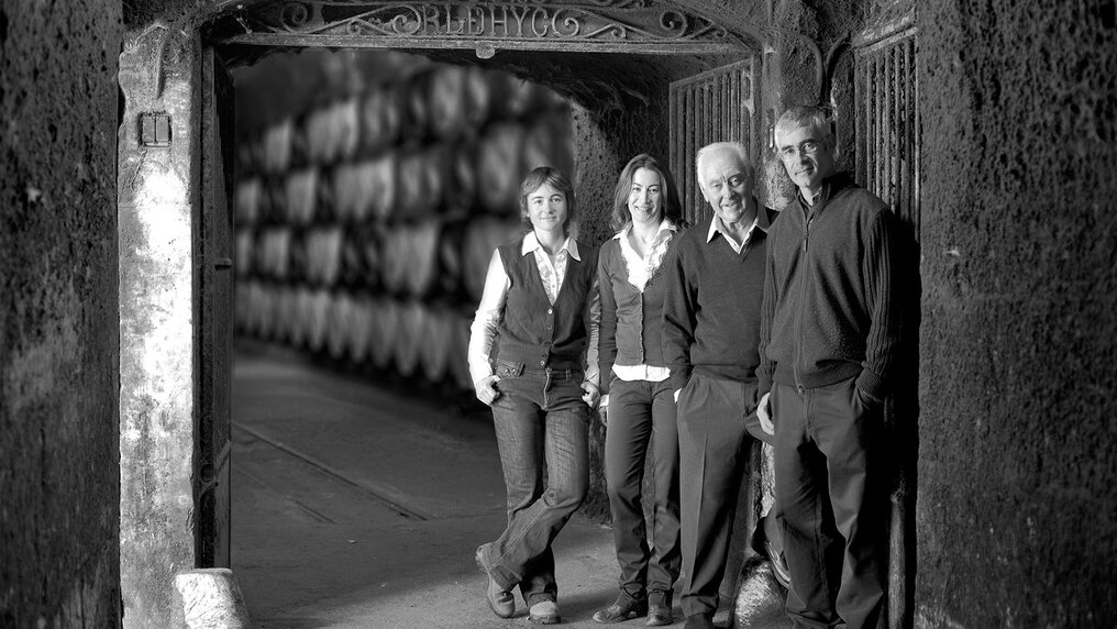 Black-and-white photograph of the López de Heredia family in front of the original iron gate at the traditional wine cellar.