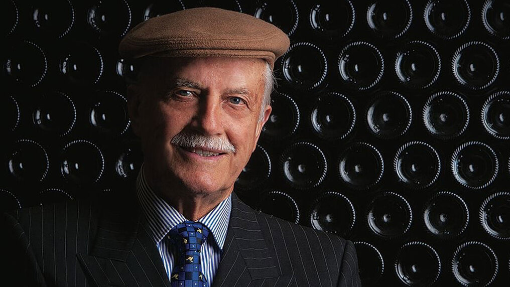 Portrait of Emidio Pepe in front of stacked wine bottles