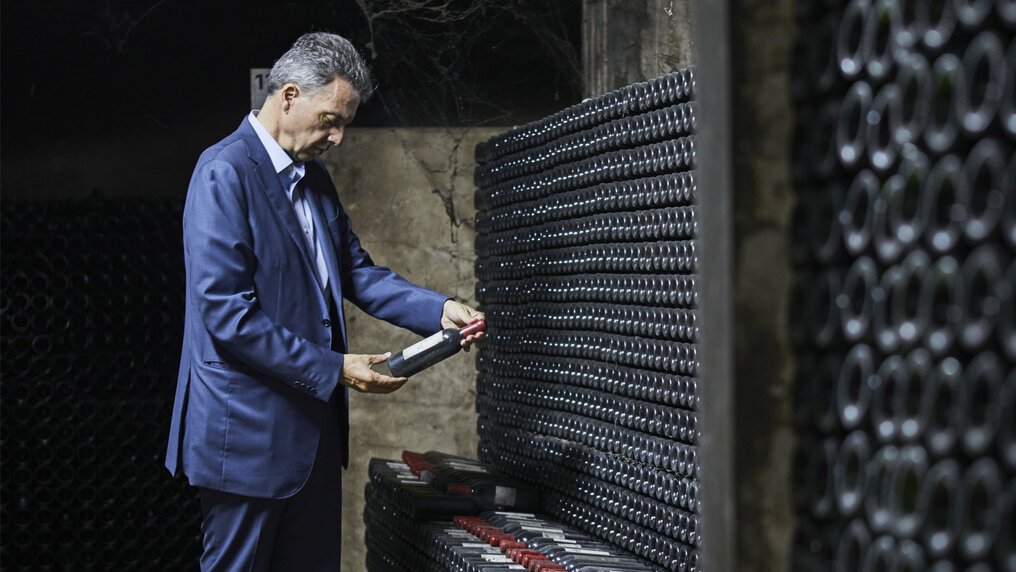 Gaston Hochar stands in the wine cellar of Chateau Musar and examines a wine bottle in his hand