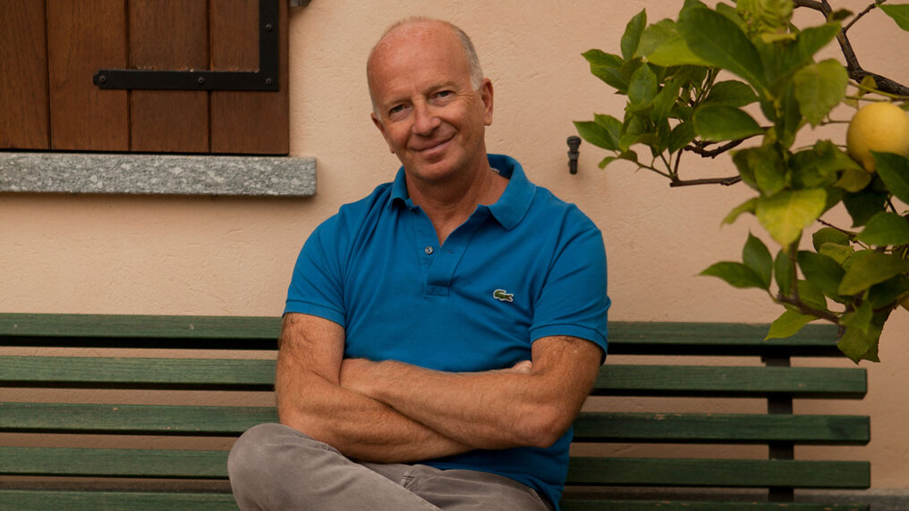 Portrait of Paolo Saracco on a bench in front of his winery