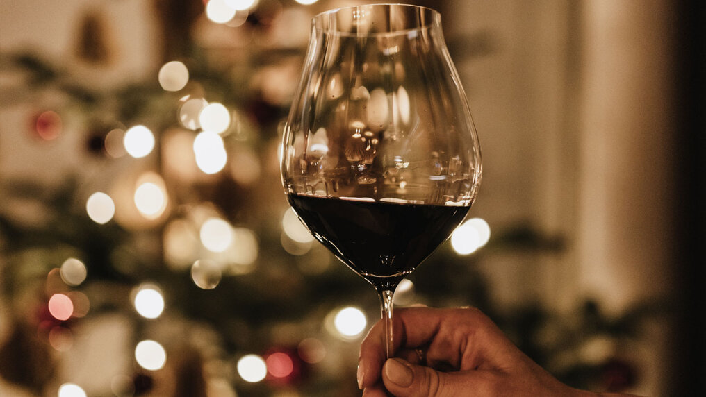 Rotweinglas mit festlicher Weihnachtsdekoration im Hintergrund